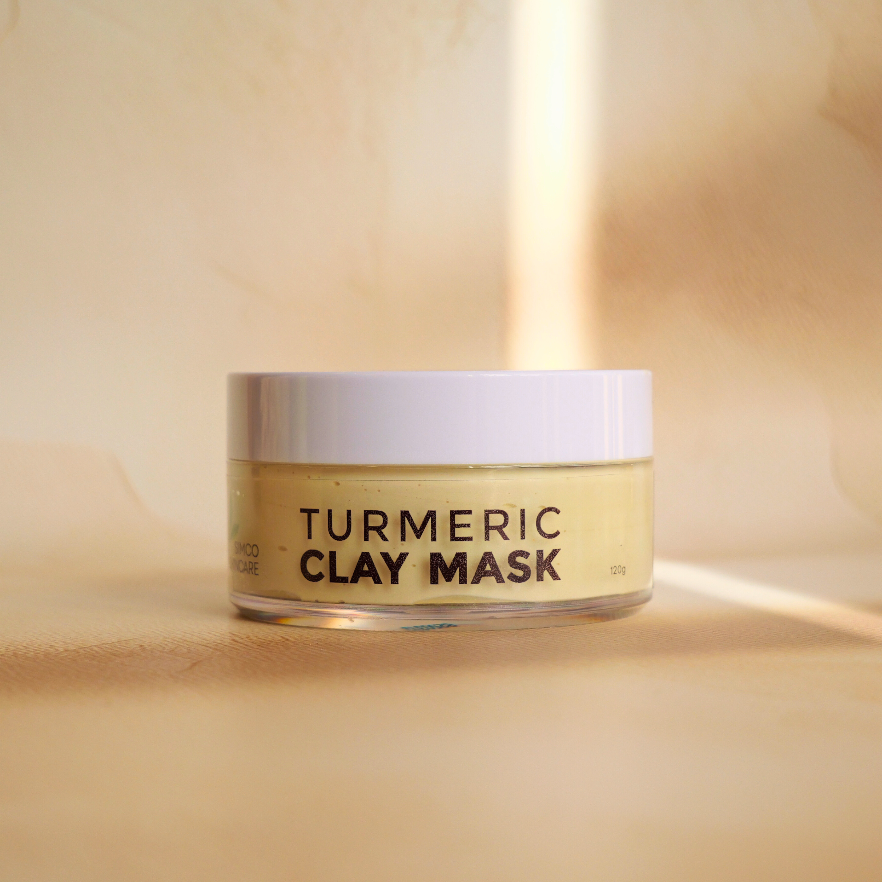 Jar of turmeric clay mask on a beige background